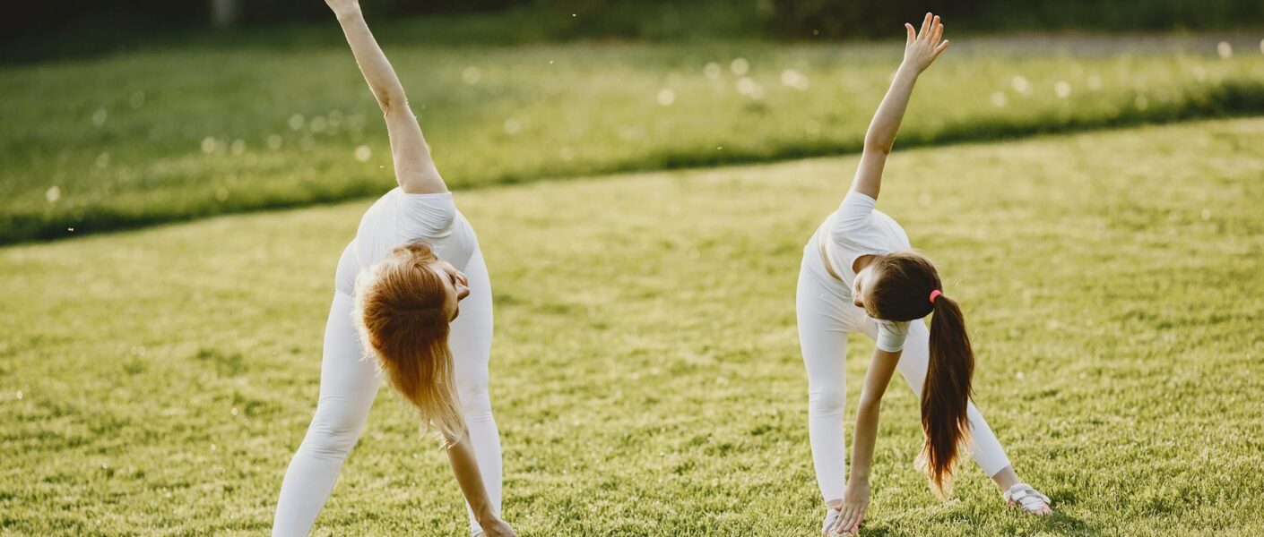 two girls exercising on the grass field with their white activewear