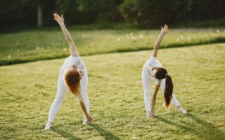 two girls exercising on the grass field with their white activewear